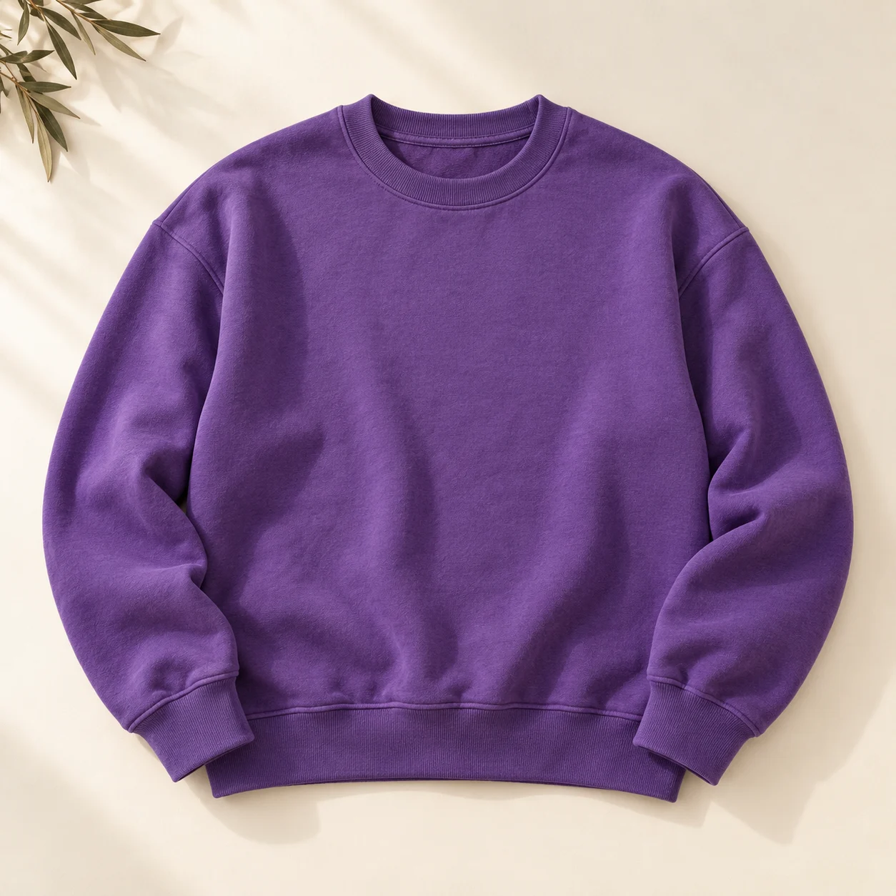 Violet cotton sweatshirt with ribbed cuffs, photographed on an ivory surface